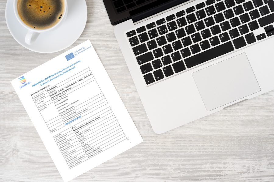 A laptop and a coffee cup on a table together with a printed deliverable from CHARM-EU