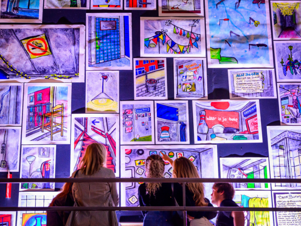 A group of people is looking at a gallery wall with fluorescent posters from below. 