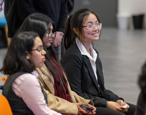 Three women sit together in an audience