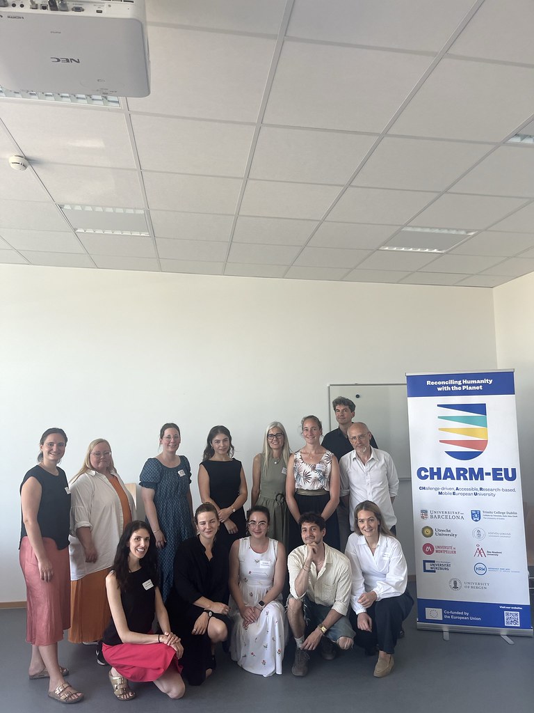 Group of participants posing beside a CHARM‑EU banner during a workshop or training event.