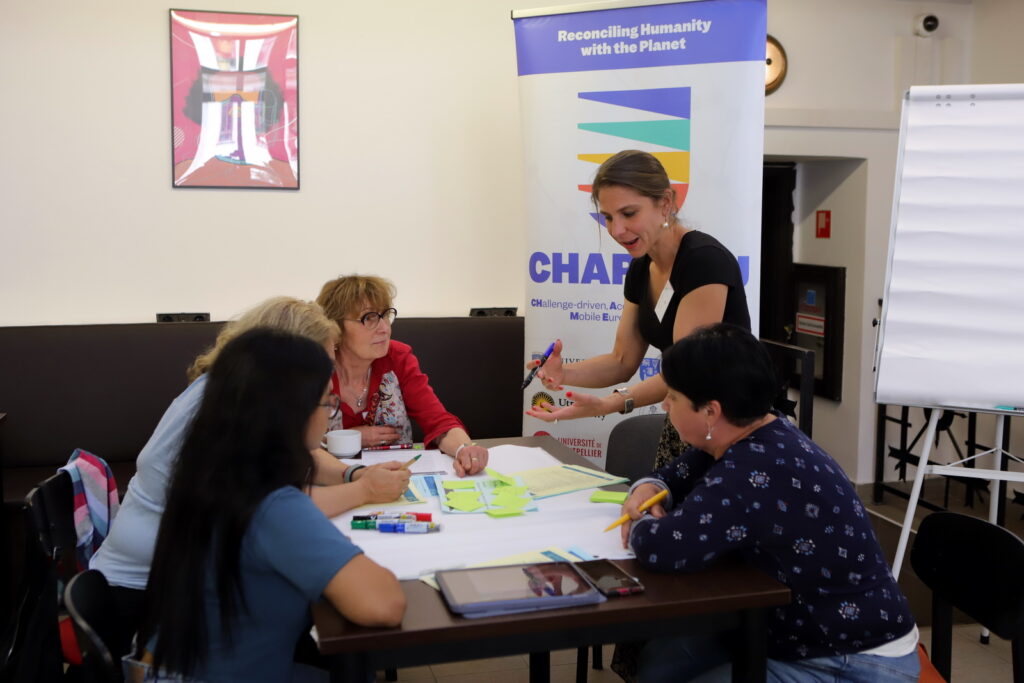 Facilitator guiding a small group discussion around a table with sticky notes and printed materials.