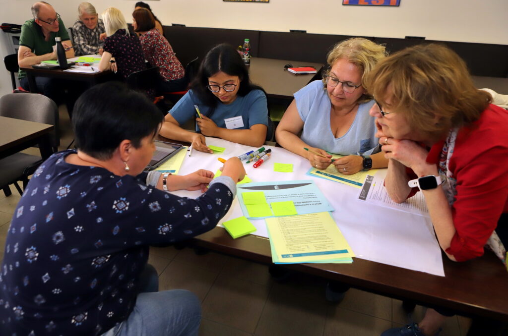 Participants collaborating in small groups, writing on sticky notes during a workshop activity.