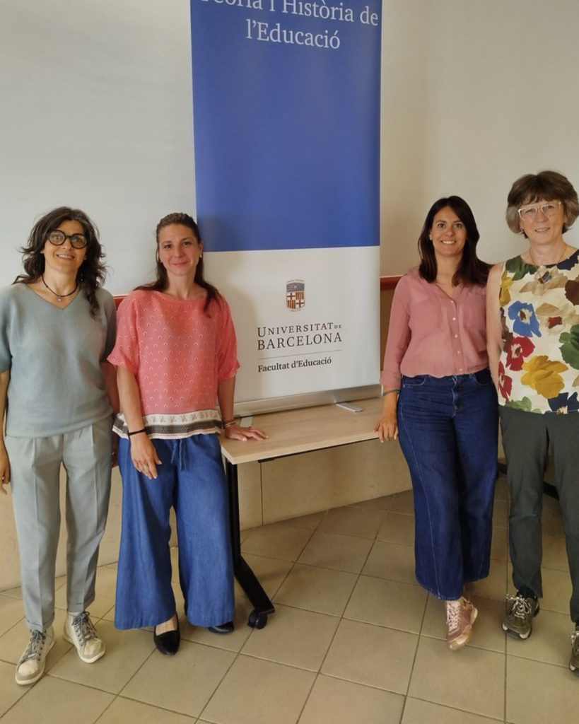 Four people standing next to a Universitat de Barcelona Faculty of Education banner in an indoor setting.
