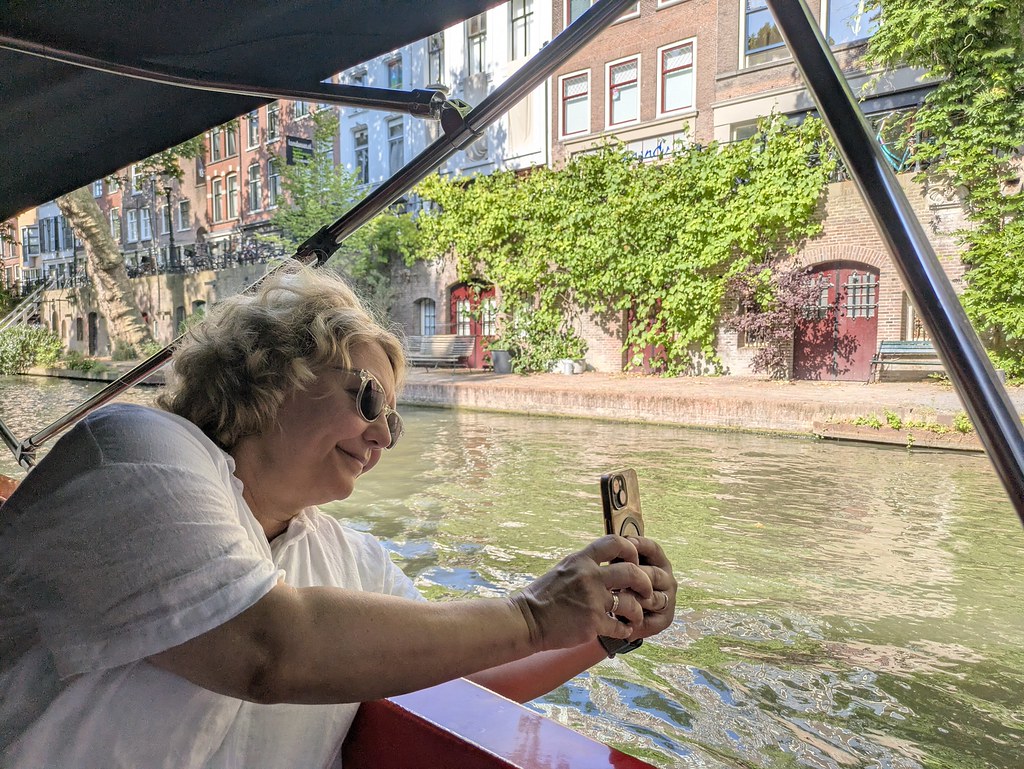 Woman in a boat taking a picture with her phone. 