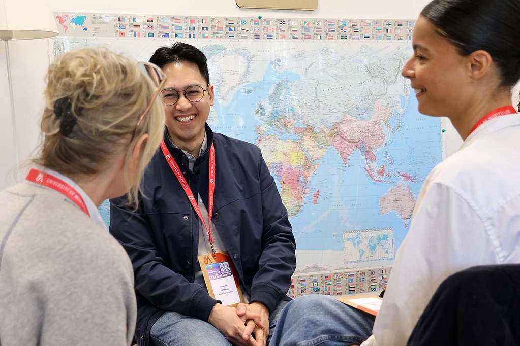 Small group discussion in front of a world map during a CHARM‑EU networking activity.