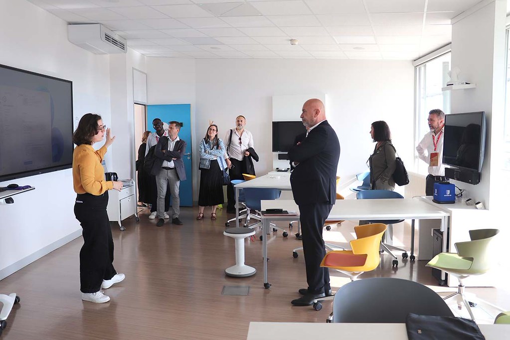 Visitors touring a modern classroom while a presenter explains the room’s technology and learning environment.