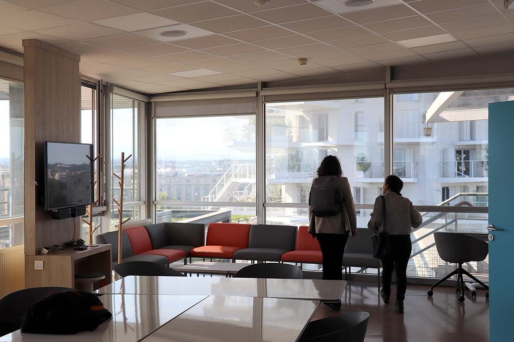 Modern collaborative learning space with large windows, tables, and seating areas overlooking the city.