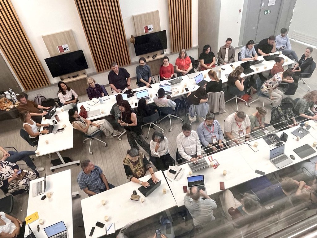 Overhead view of participants working on laptops during a collaborative CHARM‑EU workshop session.