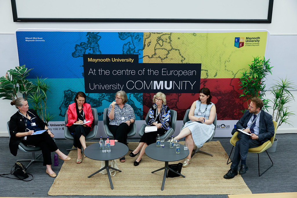 Panel discussion at the 4th Forum of the European Universities Initiative at Maynooth University, with participants seated on stage in front of a backdrop promoting the European university community.