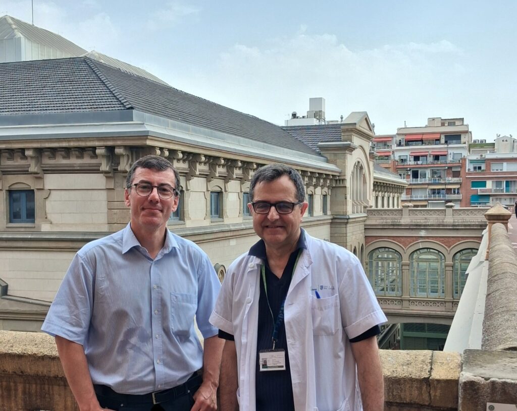Two professionals standing on a terrace outside a university hospital building.