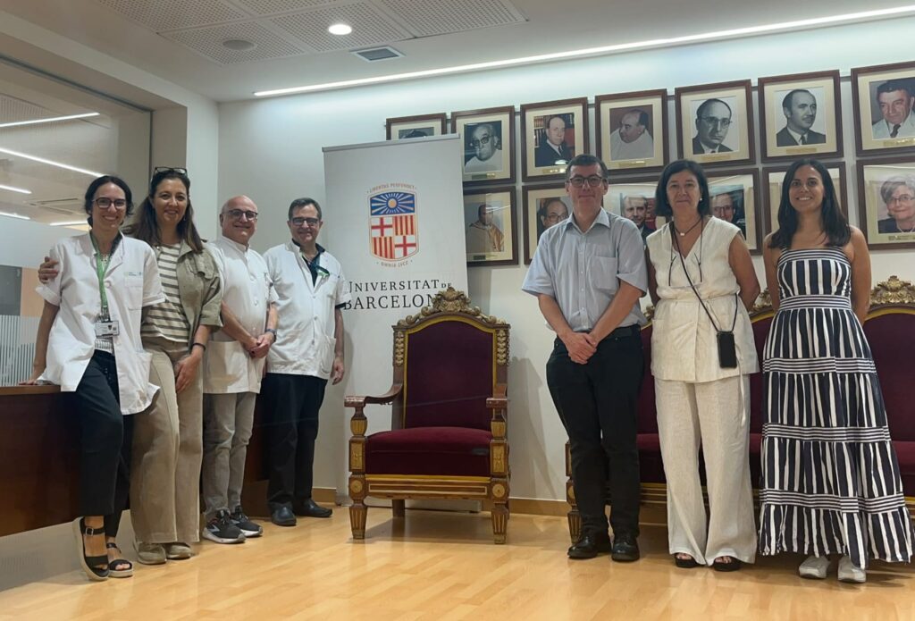 Group photo of visitors and university staff standing beside a Universitat de Barcelona banner.