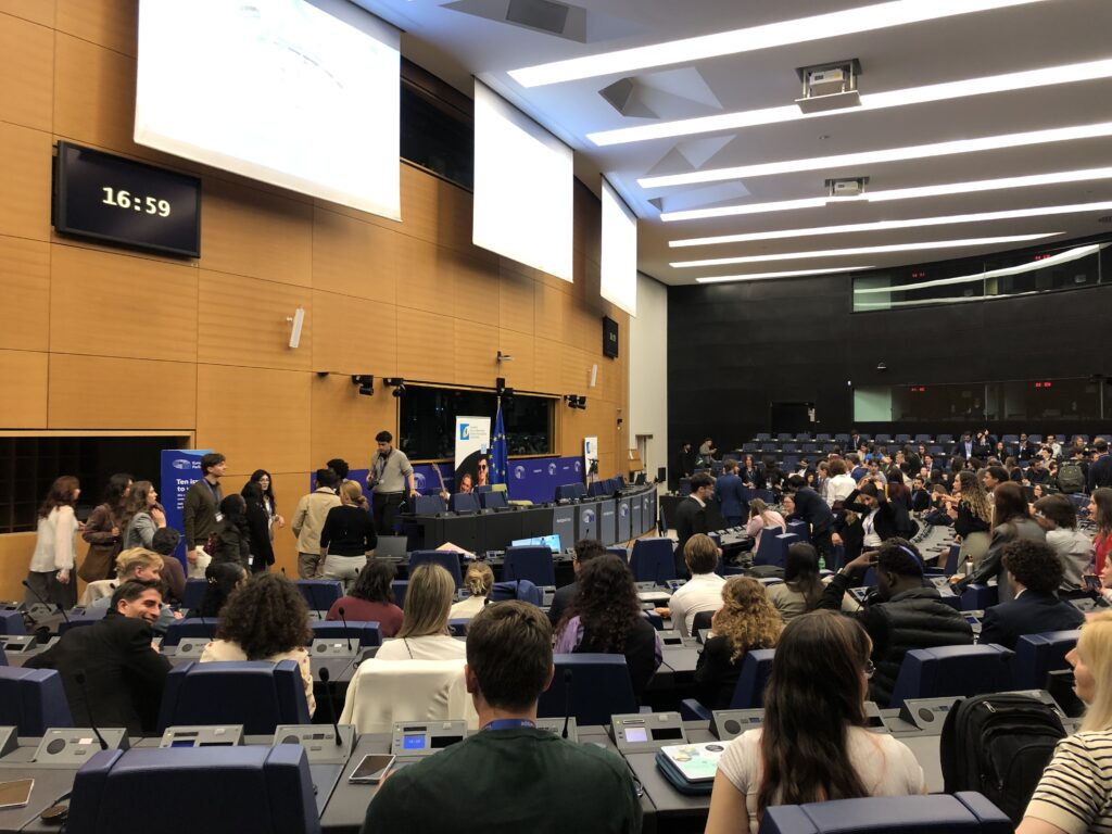 Participants attending a panel discussion inside the European Parliament chamber.