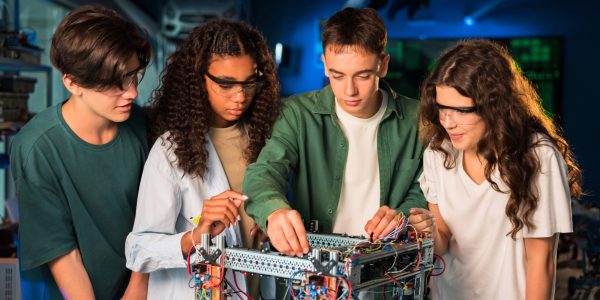 Group of young people doing experiments in robotics in a laboratory. Girls in protective glasses
