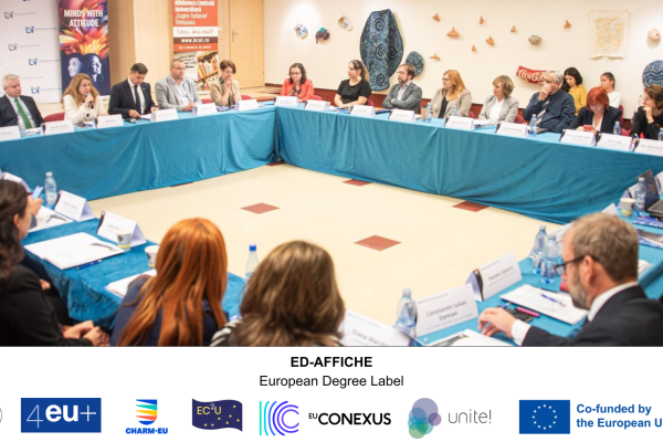 Big round table with approximately 27 persons  discussing about the European Degree label - ED-AFFICHE and the logos from the full partners UnaEuropa, 4EU+, CHARM_EU, EC2U, EU-CONEXUS, Unite! and the Co-funded by the European Union logo