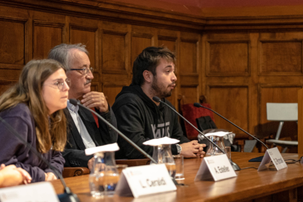 4 people sitting in a conference table talking about Citizen Science and another person standing up in the podium next to the table.