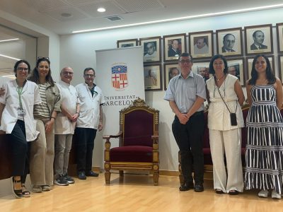 Group photo of visitors and university staff standing beside a Universitat de Barcelona banner.