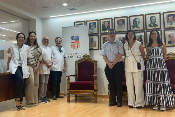Group photo of visitors and university staff standing beside a Universitat de Barcelona banner.