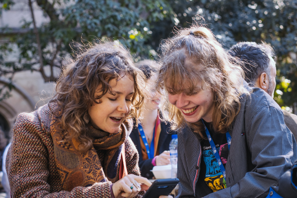 Two women laughing and looking at their phone