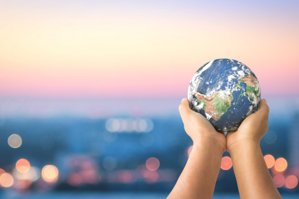 Human hand holding earth globe over blurred city night background.